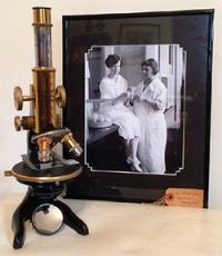 Vintage microscope next to a framed black-and-white photo.